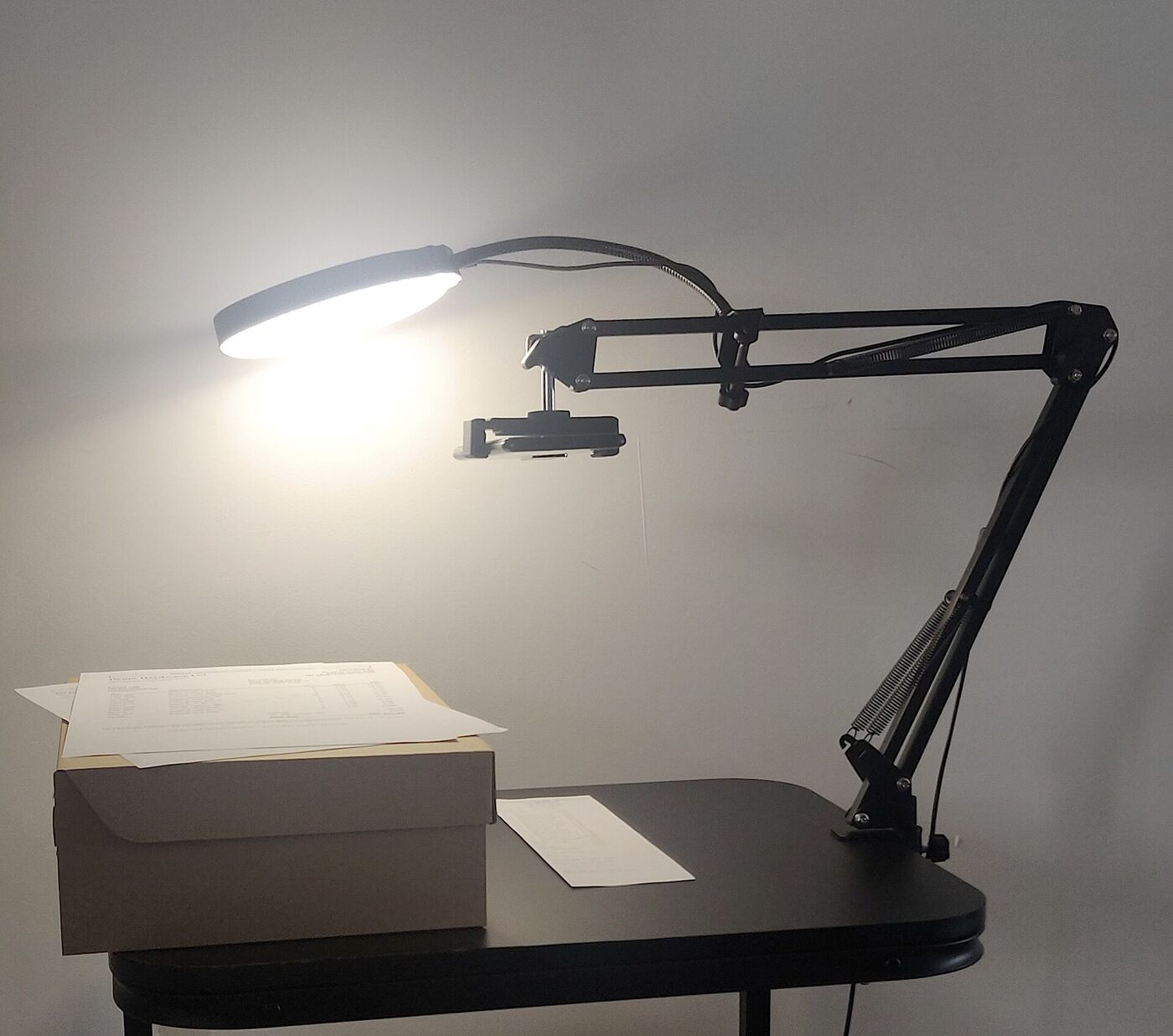 Phone on a stand with a ring light, over papers on a box